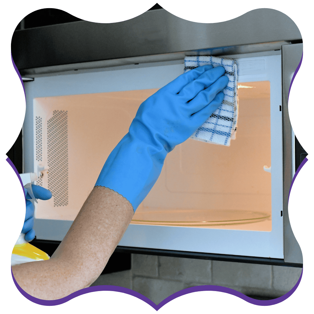 Professional cleaner sanitizing the interior of a microwave during a deep cleaning service
