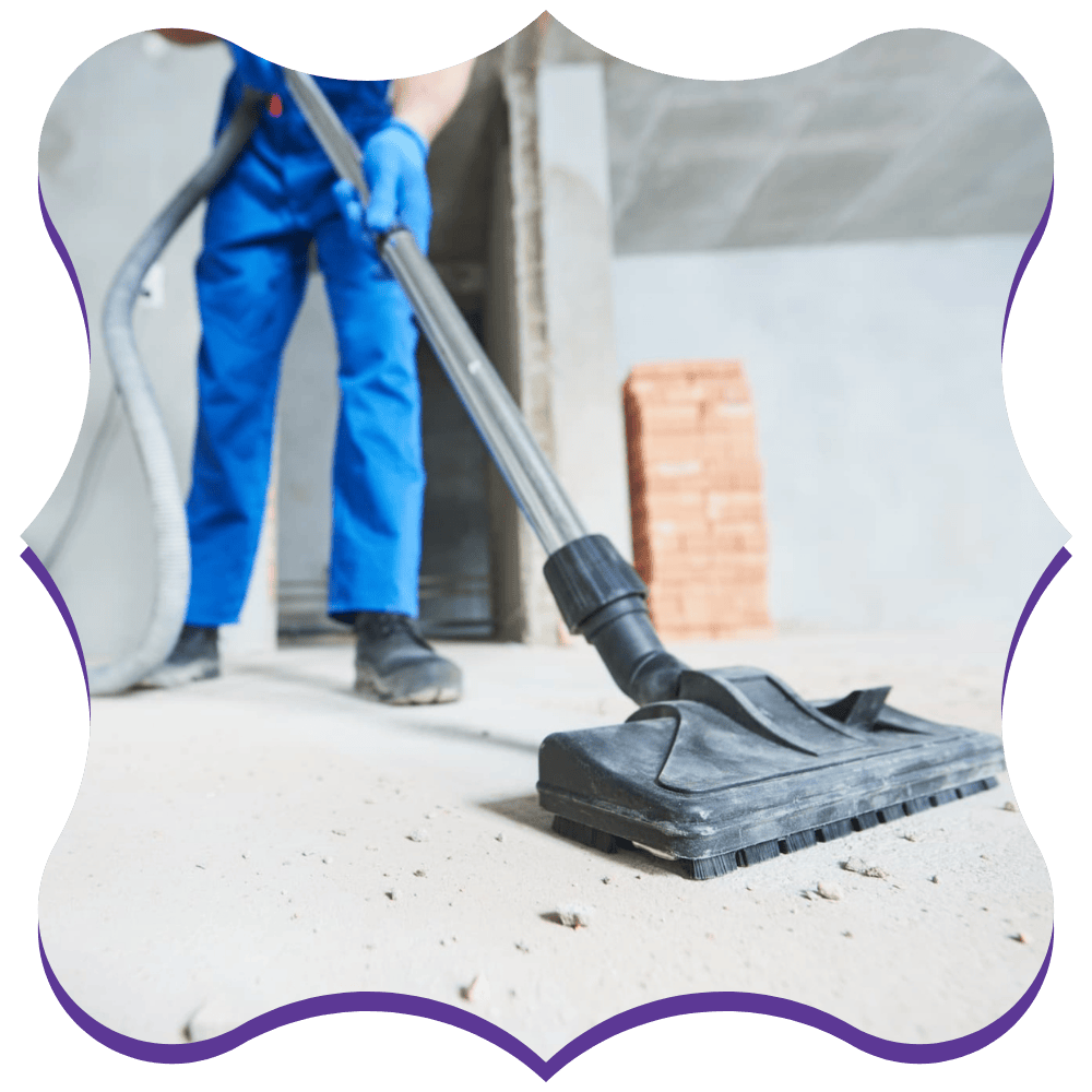 Worker vacuuming fine dust from a cement floor during post-construction cleaning